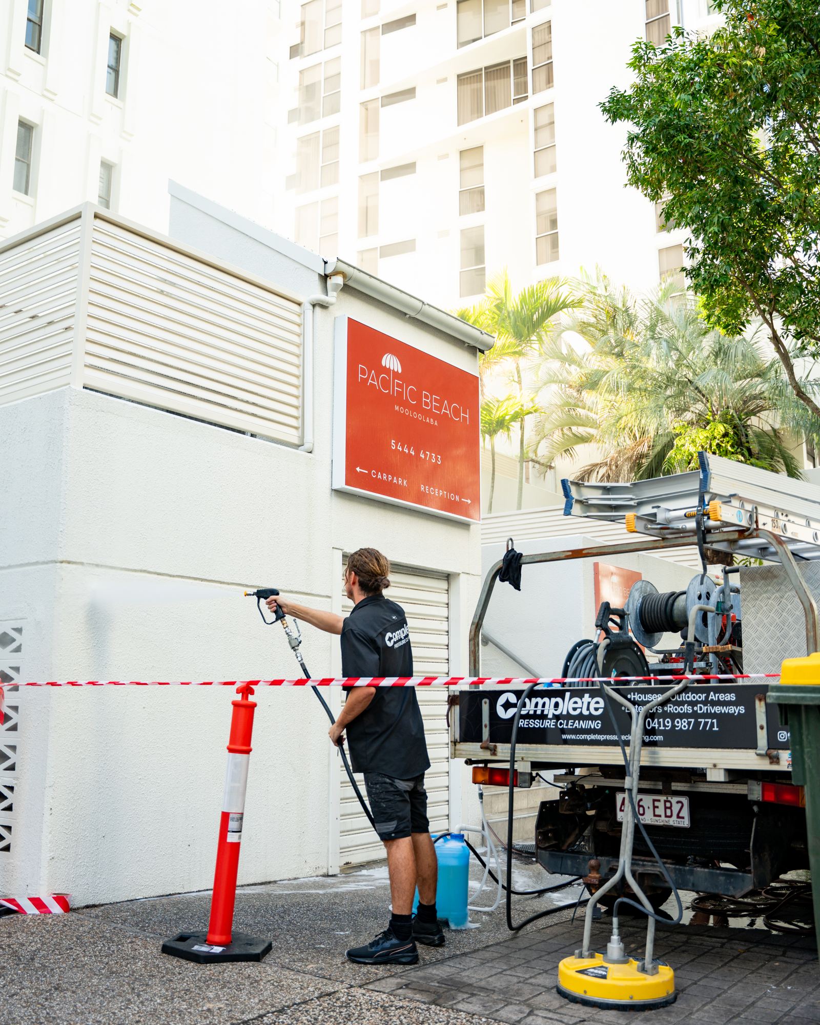 Complete Pressure Cleaning operator cleaning a footpath behind safety barriers at Pacific Beach