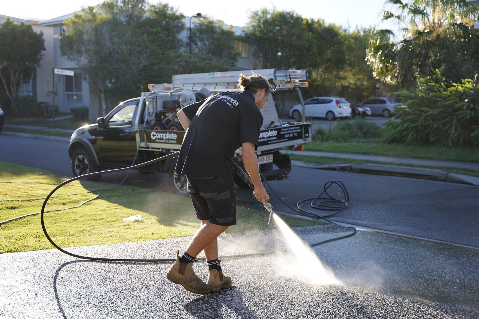 Pressure cleaning a driveway with the work ute parked behind