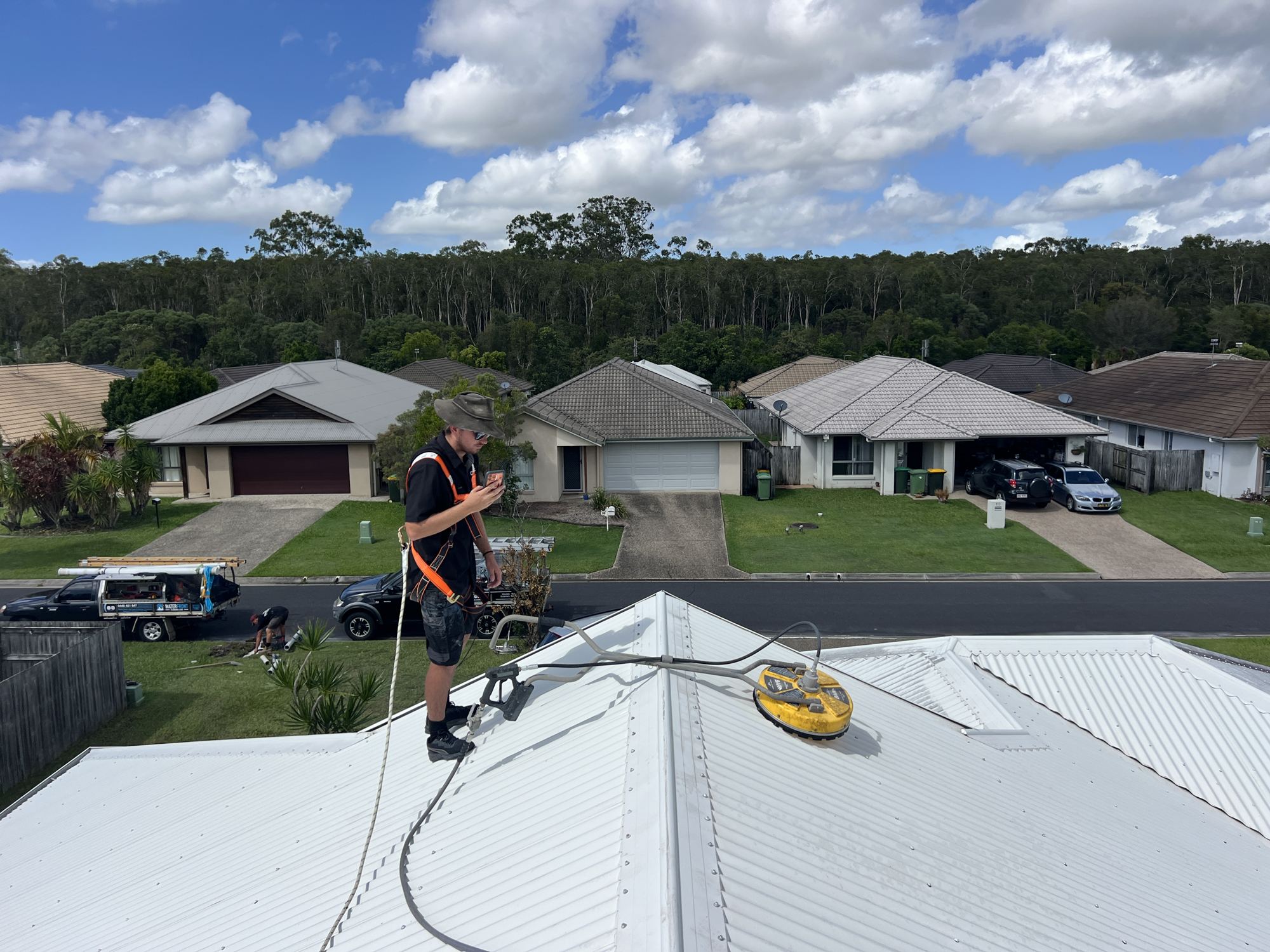 Roof cleaning in a safety harness with a surface cleaner