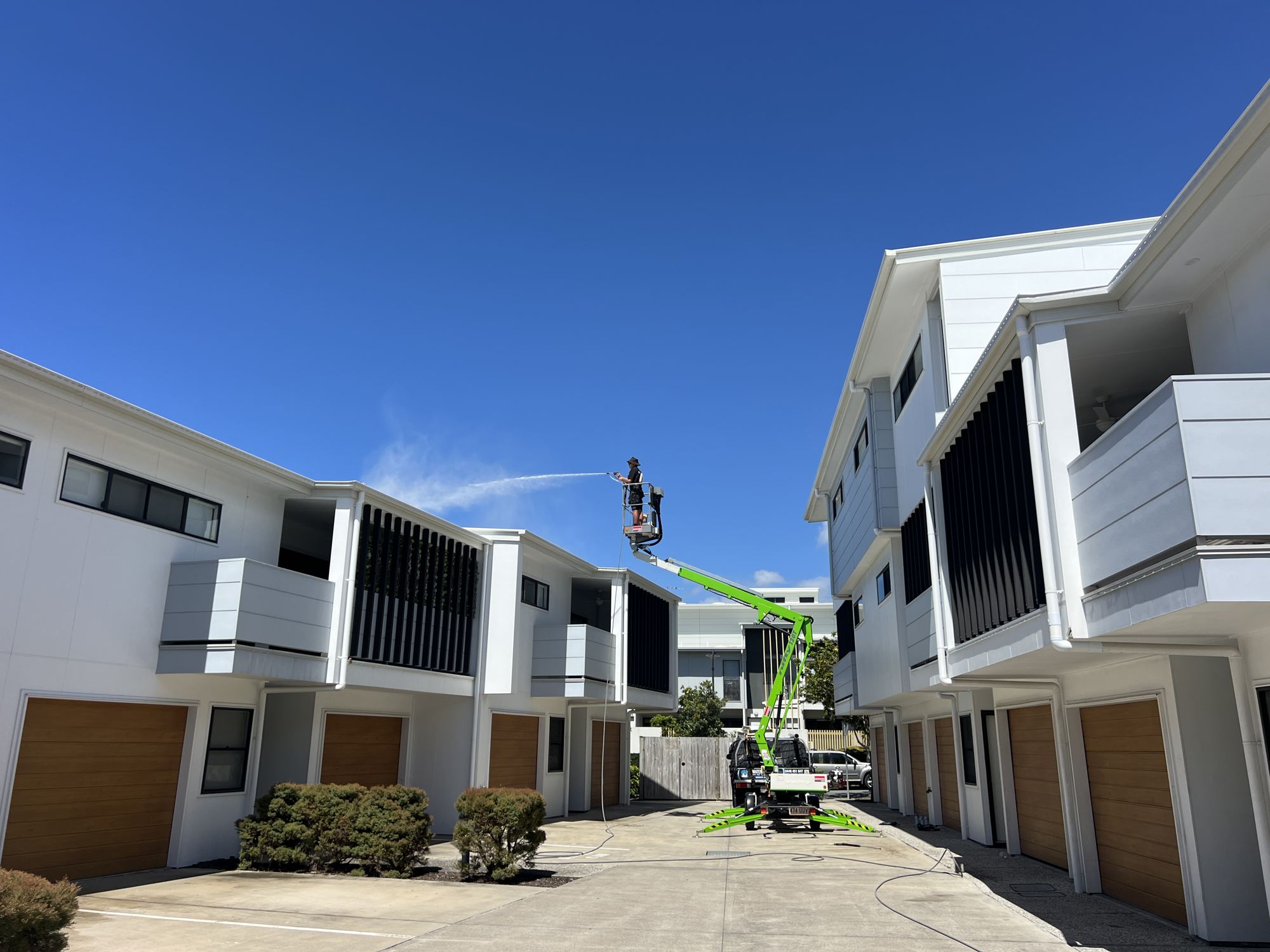 Boom lift washing a row of townhouses